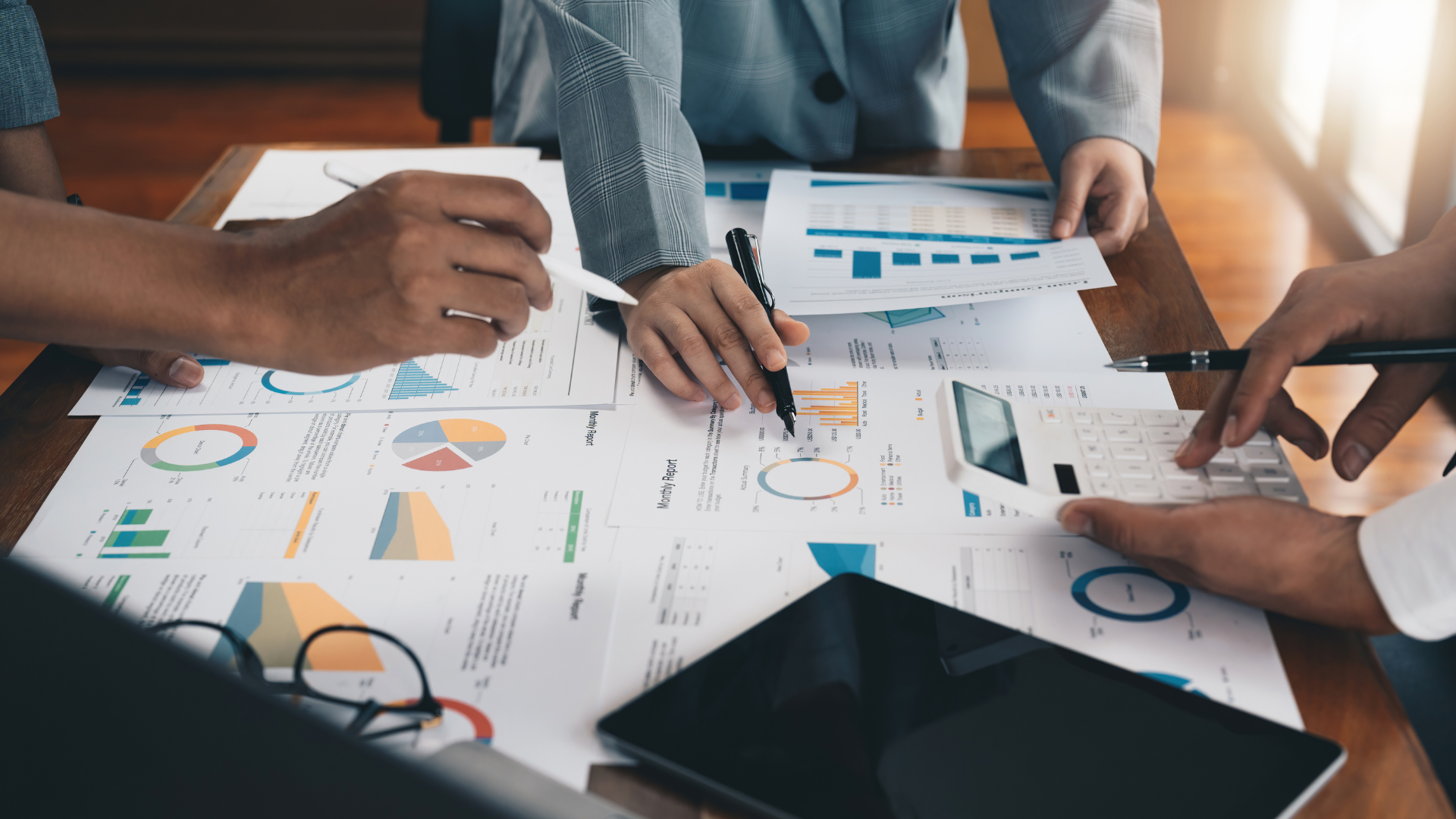 people meeting around a table discussing charts and reports